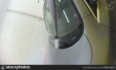 Slow Motion: High pressure washer cleaning car spraying water jet on vehicle surface in garage or washing service centre