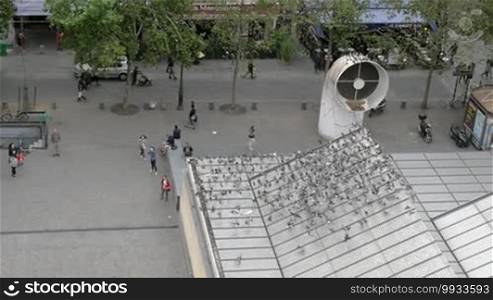 Slow motion of a huge flock of pigeons flying around the square near the Centre Georges Pompidou in Paris, France. People watching numerous birds