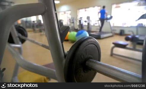 Slow motion of a man putting on a weight plate on barbell before starting bench press exercise