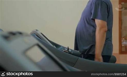 Slow motion of a man working out on a modern exercise machine in the gym. Treadmill training keeps him fit