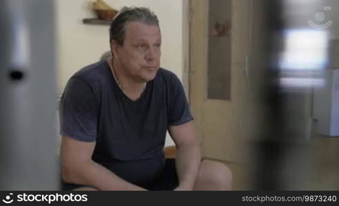 Slow motion of an exhausted sweaty man having a break after a hard workout. He is staring straight ahead and breathing deeply