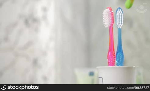Slow motion of children's toothbrush appearing with two ones of adults. Concept of a baby birth in the family