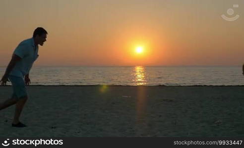 Slow motion of father and son running to each other on the beach and then dad spinning him on the background of sunset and sea