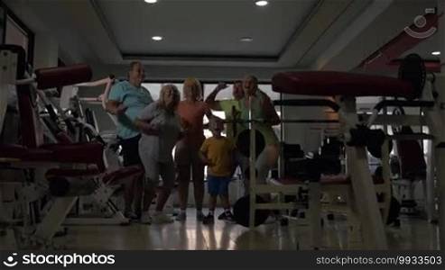Slow motion of happy big family giving high-fives and showing thumbs-up after training in the gym. Child, parents, and grandparents motivating to go in for sports