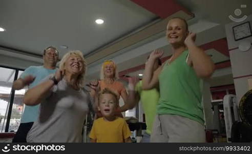 Slow motion of happy family in the fitness center. Child, senior, and young people showing excitement after training together and motivating to keep fit with sport