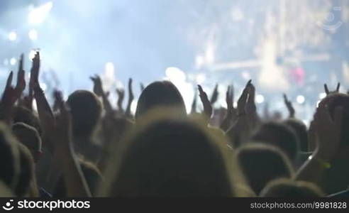 Slow motion shot of a concert audience applauding to the artist during the show.