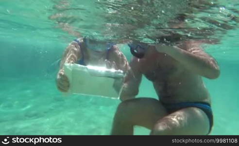Slow motion shot of a couple making a selfie with a tablet PC while snorkel diving.
