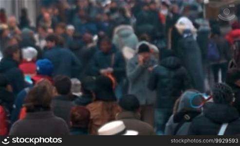 Slow motion shot of city people walking outdoors on a cold day. Shot is made with slight defocus.