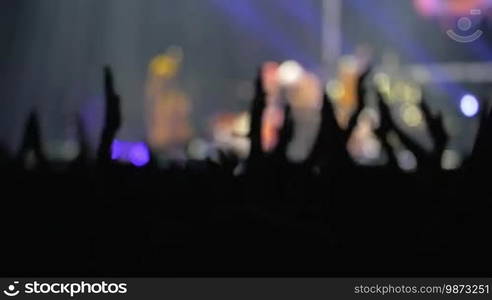 Slow motion shot of hands raised over the head to applaud to the artist on the stage.