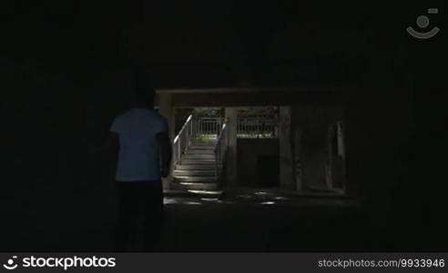 Slow motion steadicam shot of a young man running upstairs in the hotel. He passing several outdoor stairways