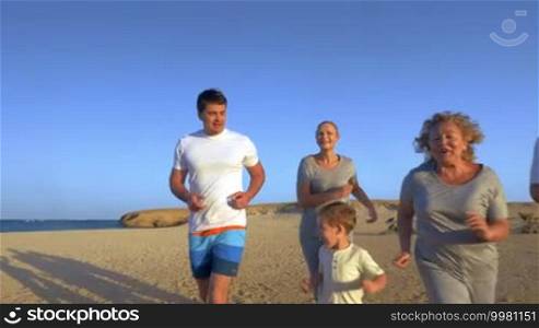 Slow motion steadicam shot of happy friendly family running at the seaside during vacation. Leisure time with sport to be healthy