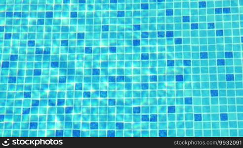 Small blue tiles on the floor of the swimming pool, there are sun flecks on the water.