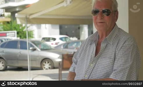 Smiling senior man in sunglasses on the street.