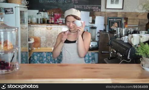 Smiling young barista making coffee in a cafe using professional equipment