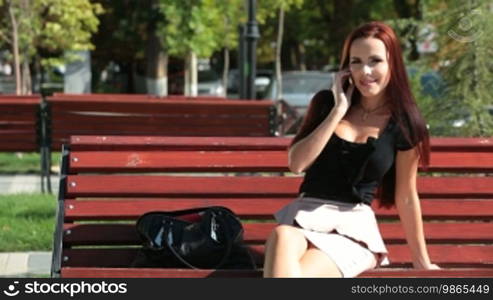 Smiling young woman talking on the cell phone, looking at camera