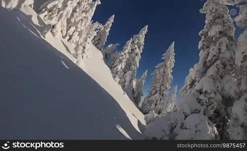 Snowboarder rides through deep powder snow in backcountry wilderness