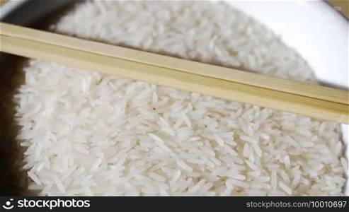 Some rice is turning in a bowl in front of the camera, the scene has chopsticks as decoration