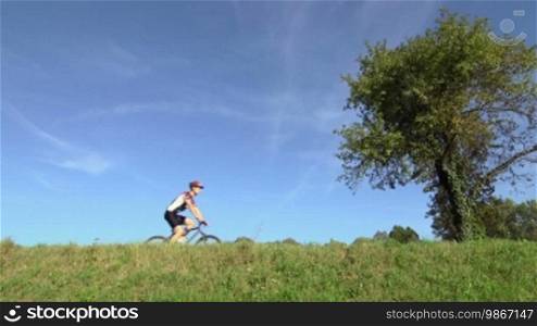 Sport activity: young adult cyclist riding mountain bike in the countryside. Sequence