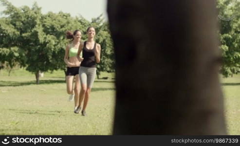 Sports and fitness with two female teenagers and friends exercising and working out in city park. Dolly shot, sequence