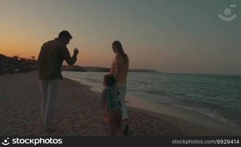 Steadicam shot of a family walking on the beach late in the evening.