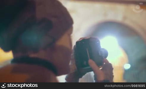 Steadicam shot of a female traveler filming Roman Coliseum with retro video camera at night. Places to visit in Italy