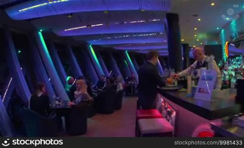Steadicam shot of interiors of revolving restaurant Top 180 at night and its guests.