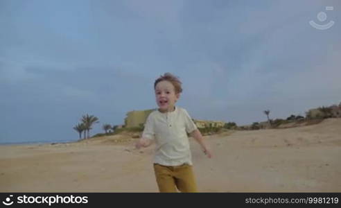 Steadicam slow motion shot of a boy running toward the camera. He's smiling and enjoying himself.