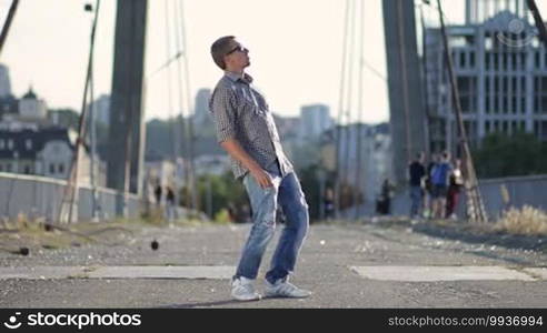 Street dancer dressed in casual clothes performing freestyle dance over industrial background