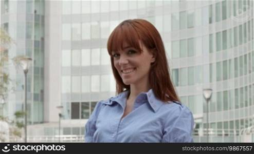 Successful people at work, confident businesswoman with red hair smiling at camera near office building. Sequence