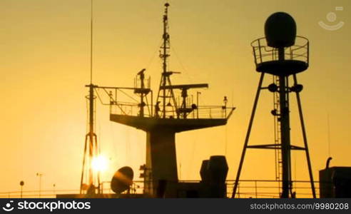 Sun at dawn illuminates the ship masts and superstructure