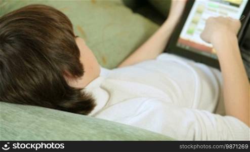 Teen Boy Playing Computer Games On Tablet PC At Home