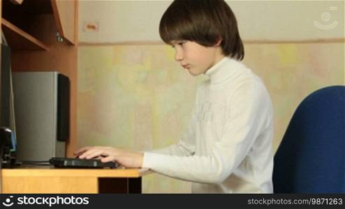 Teen Boy Playing Desktop Computer Games At Home, Medium Shot