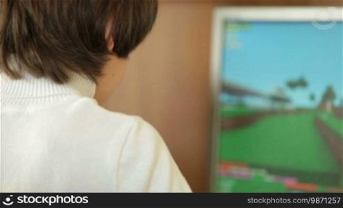 Teen Boy Playing Desktop Computer Games At Home, Over The Shoulder View