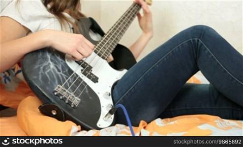 Teen Girl Playing Bass Guitar At Home