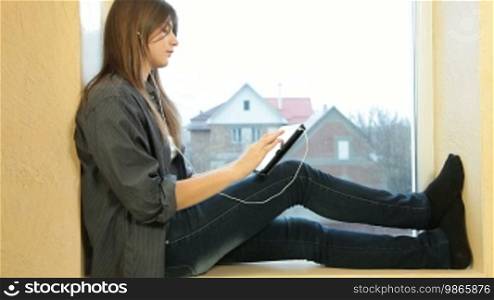 Teenager girl listening to music on a digital tablet at home
