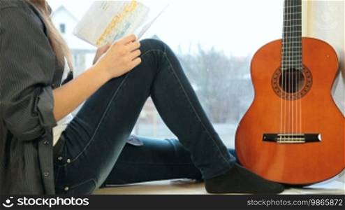 Teenager girl studying guitar fingerings at home
