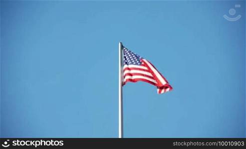 The American flag hangs limp on the mast, little wind, little energy