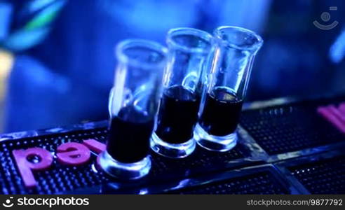 The barman makes a cocktail shot. A man is preparing a drink. Alcohol. A party. A young man is working at a bar counter.