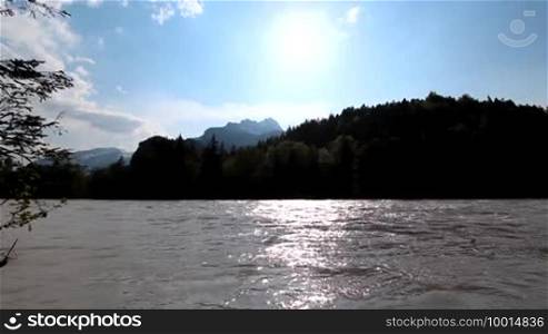 The Bavarian river Lech, surrounded by mountains and backlight from the sun, Allgäu, Bavaria - the river Lech in front of the Alps in backlight