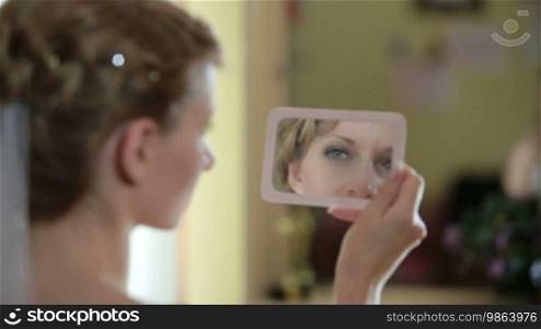 The bride looks in the mirror after the makeup