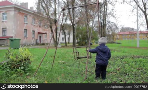 The little boy is swinging an old swing.