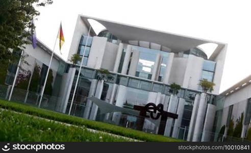 The seat of the German Chancellor, the so-called Chancellery or the Federal Washing Machine in Berlin slang with waving flags and trees in the foreground