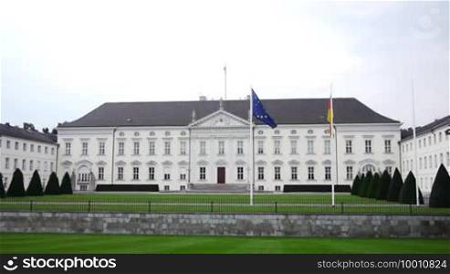 The seat of the German President with its garden is shown, in front of the building the German and the European Flag are waving