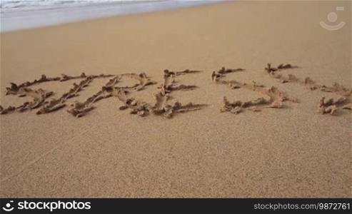 The word "Stress" written in the sand on the beach