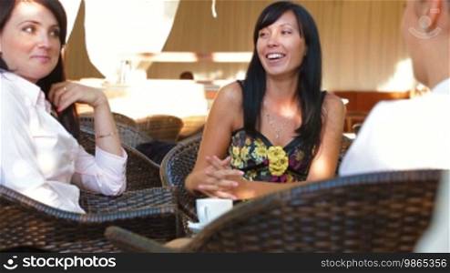 Three female friends immersed in conversation at urban cafe