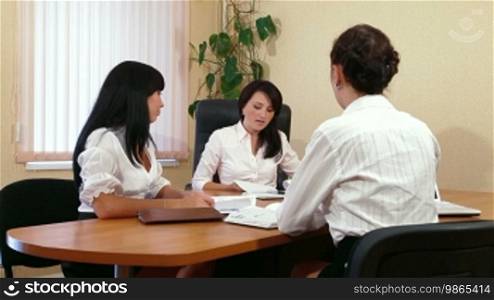 Three young women discussing business issues in office