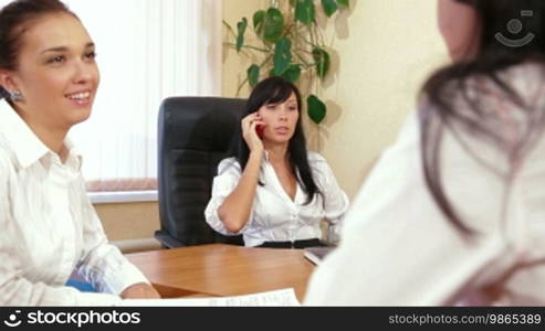 Three young women discussing business issues in office, focus on background