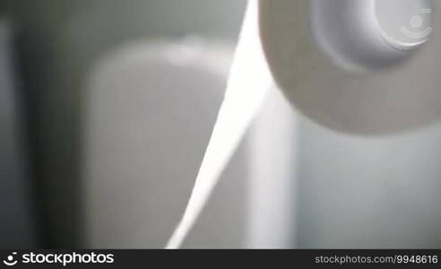 Tilt and dolly macro shot of unrolling a toilet paper