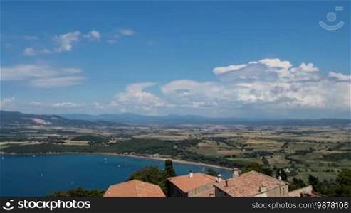 Time-lapse of clouds near the sea with yachts. In the background scenic beautiful mountains and fields. Italy, Tuscany, Piombino