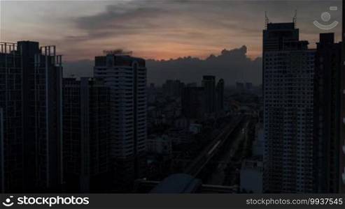 Time lapse shot of cityscape with skyscrapers and buildings in the foreground and industrial smog under the city in the background in the evening. Bangkok, Thailand
